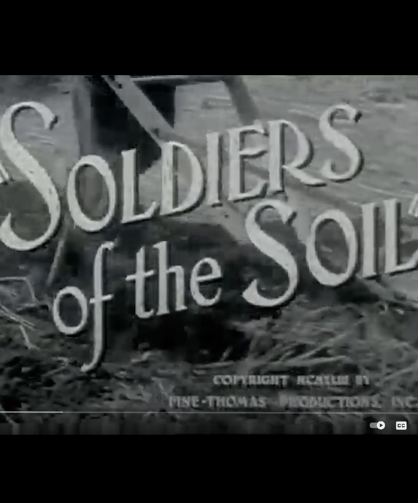 Movie screen still in black and white with graphic text that reads "Soldiers of the Soil"